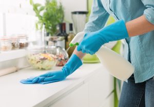 Woman,Cleaning,And,Polishing,The,Kitchen,Worktop,With,A,Spray