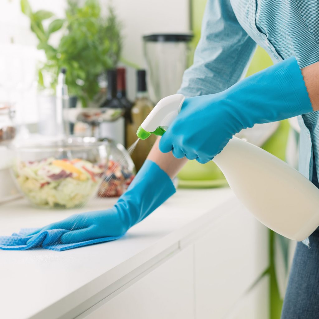Woman,Cleaning,And,Polishing,The,Kitchen,Worktop,With,A,Spray